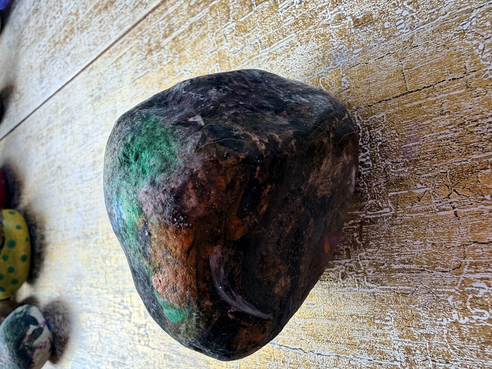 Painted stone No. 21, decorated as: Large blacky, orange splodge, green/blue/white splat