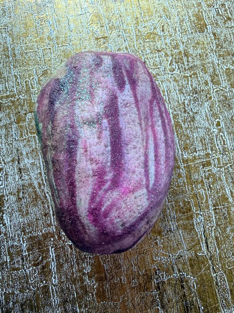 Painted stone No. 32, decorated as: Purpley finger paint with sparkle and grey stripe