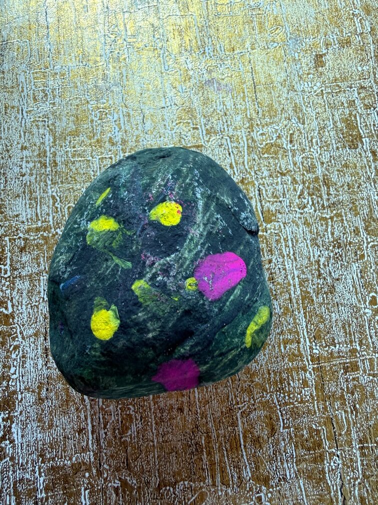 Painted stone No. 47, decorated as: Black with yellow dots and pink splodges